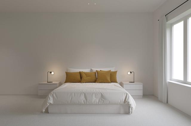 在纯白的极简主义卧室里,纯白的床上放满了马特金(matt gold)靠垫.