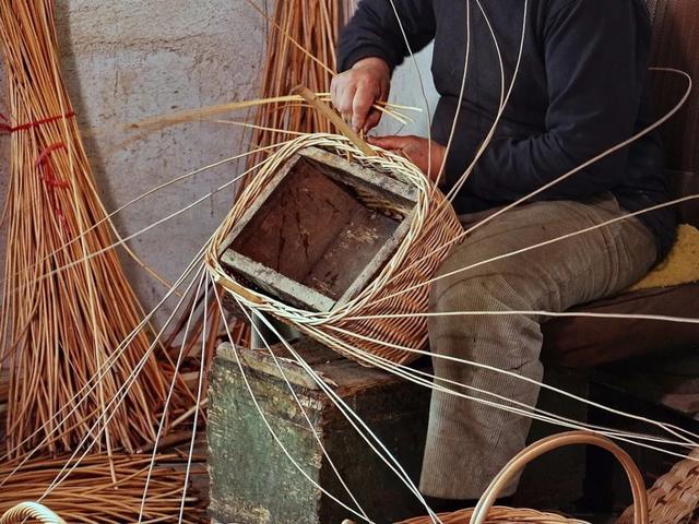 匠人拿着用粗藤打好的框架,坐定下来在暖阳之下,和煦的风中,细密地编