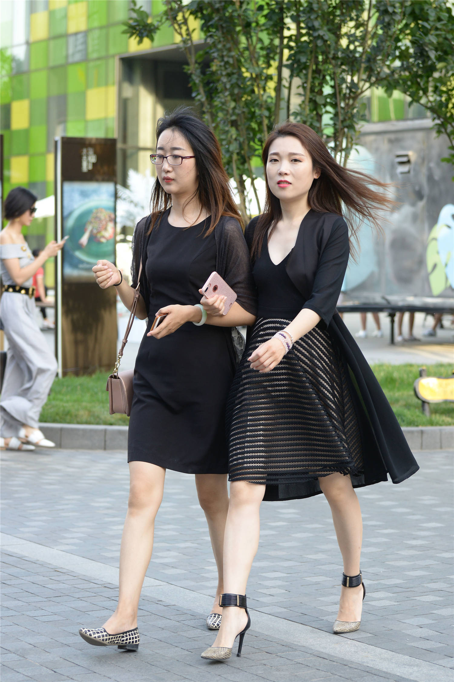 闺蜜逛街选择黑色连衣裙,一位穿着平底鞋,一位搭配高跟鞋