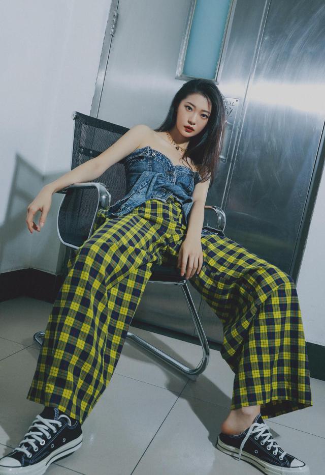 慵懒坐在椅子上的田依桐不羁率性,身穿着蓝色抹胸上衣 黄黑格纹阔腿裤