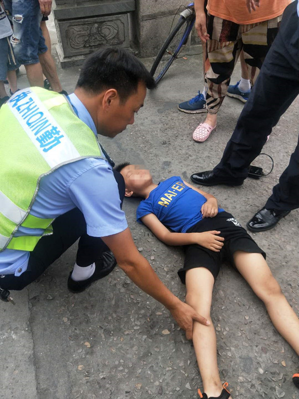 男孩摔倒晕在路中央 交警暖心守护
