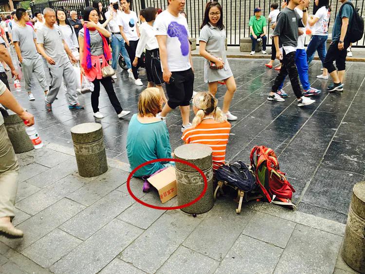 小情侣穷游到中国开始乞讨,只是坐着却很快进账丰厚