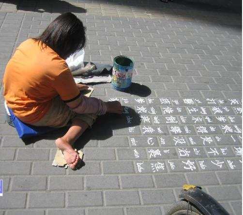 女孩乞讨不哭诉自己让人同情专心在路边写字路人看到纷纷施舍