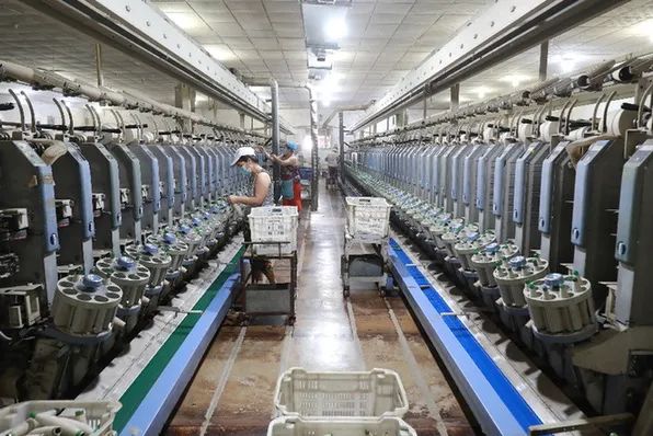 7月20日,工人在河北省滦南县长凝镇的一家纺织厂生产车间里工作.