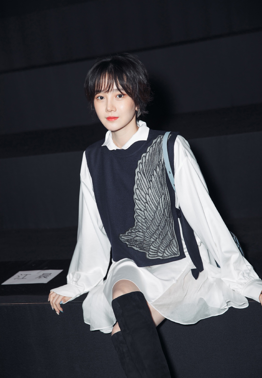 脚踩一双黑色高筒靴,直接玩下衣失踪,露出一截美腿,可以说相当高调.