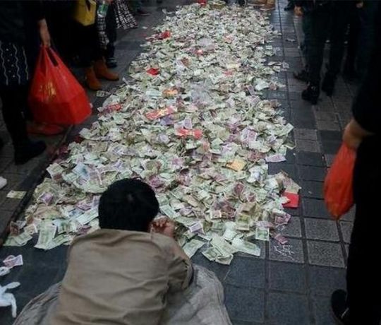 乞丐在地上放了好多乞讨来的钱路人纷纷扔钱图吉利