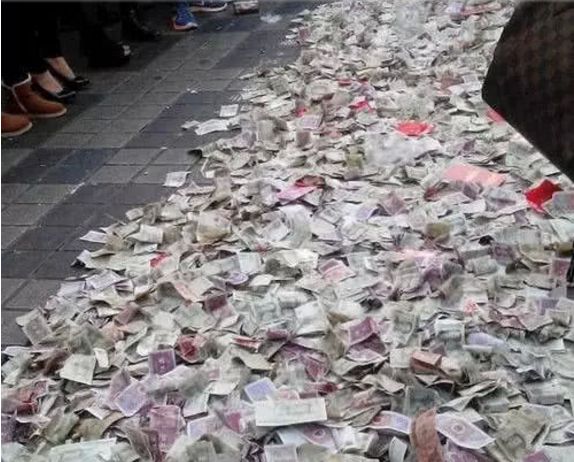 乞丐在地上放了好多乞讨来的钱路人纷纷扔钱图吉利