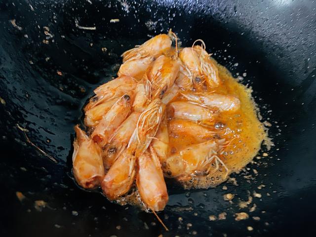 2,起锅烧油,五成热,将虾头倒入锅中翻炒,炒出虾油后,将虾头捞出扔掉