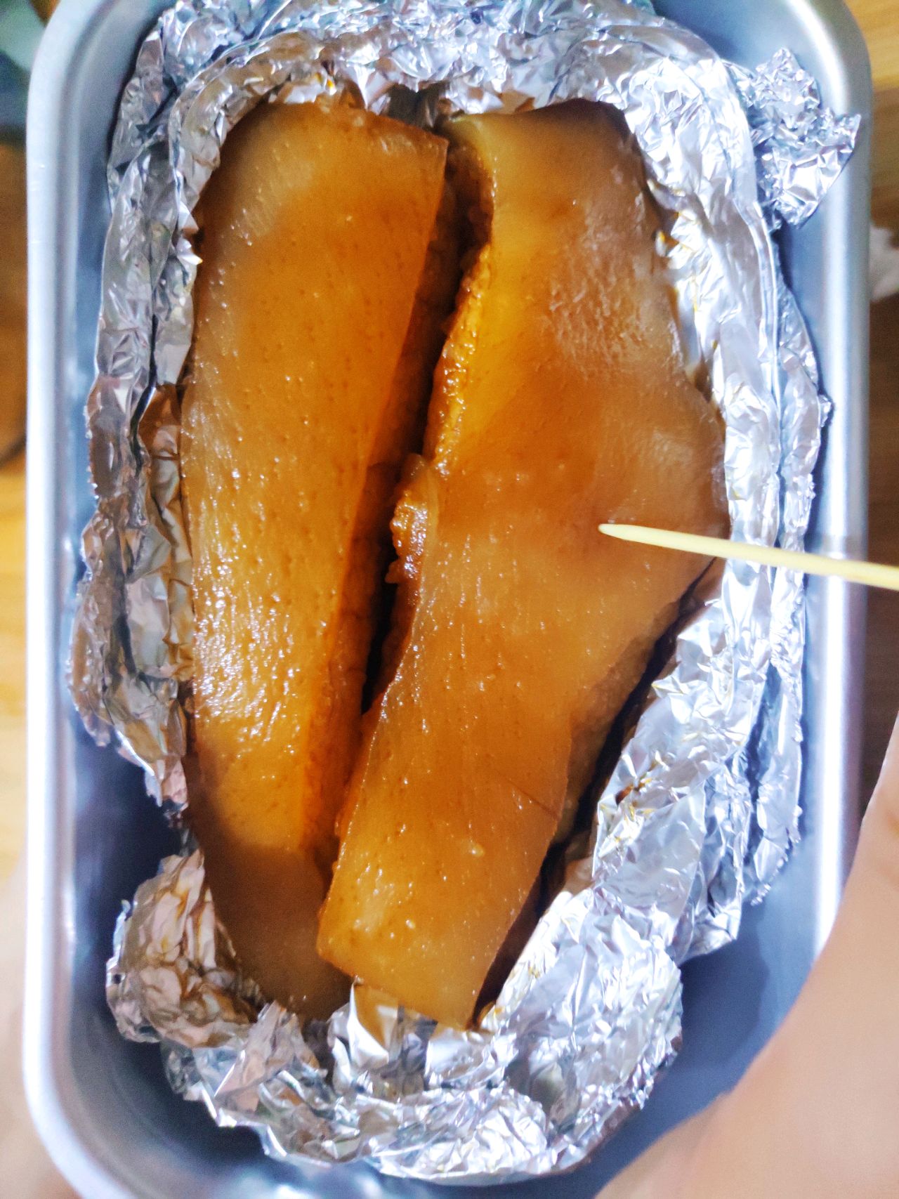 5,然后准备一个锡纸,把五花肉包起来了,然后把五花肉的皮向外,用牙签