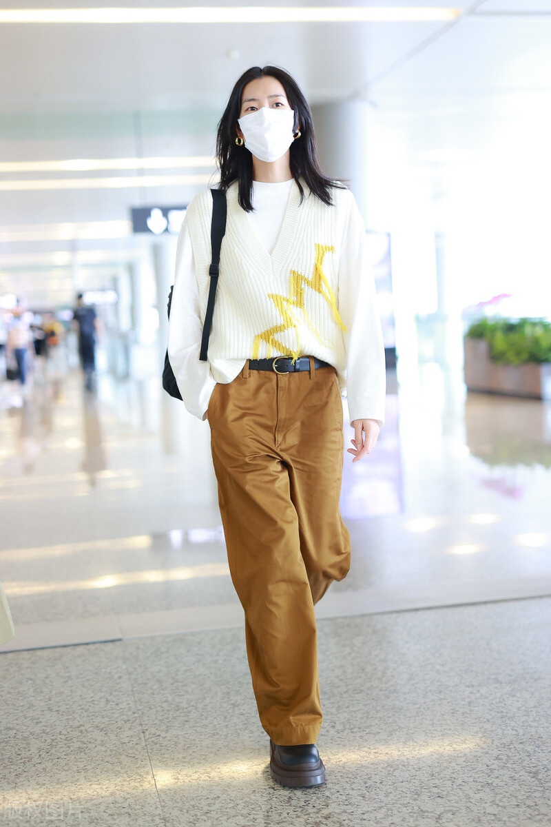 刘雯穿白色针织衫,搭配卡其色裤子,挥手打招呼尽显个人气质