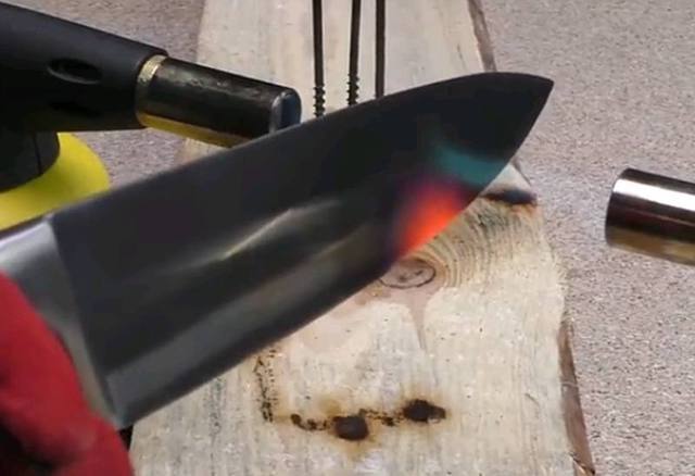 他拿来一把尖刀,放在火焰上面烧.注意,还是用的两个喷火口烧.