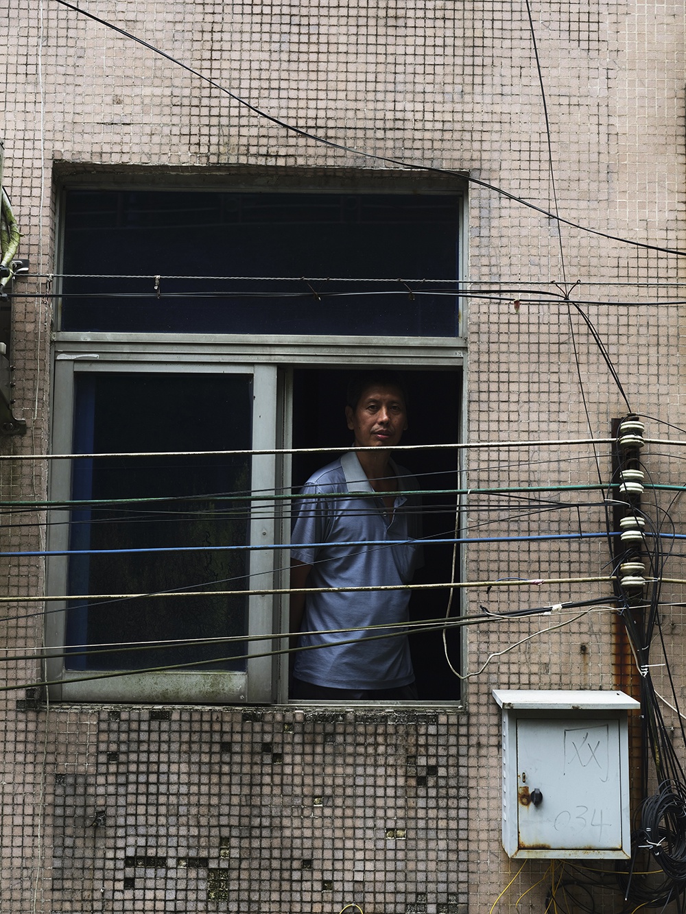 简国超在楼道窗口眺望。摄影：翟星理