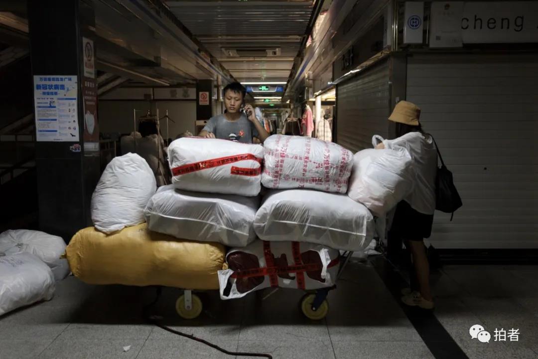 △9月26日，广州万佳服装批发市场，一名日卖两千件货的主播（右一）从阿燕的档口拿完货后，雇了一名搬运工帮忙运货。