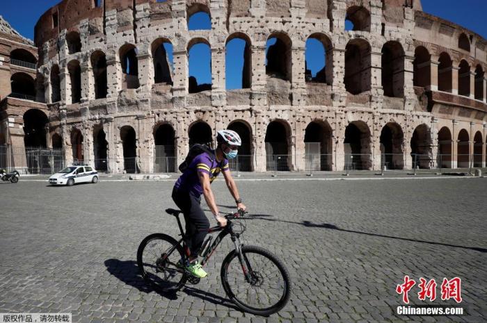 当地时间10月8日，意大利首都罗马，一男子佩戴口罩骑车经过斗兽场。