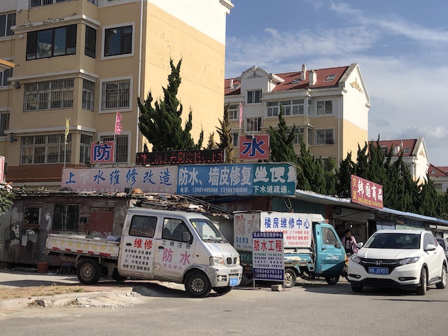 走近银滩，一路上防水、墙皮修复的店铺显眼地林立在路旁