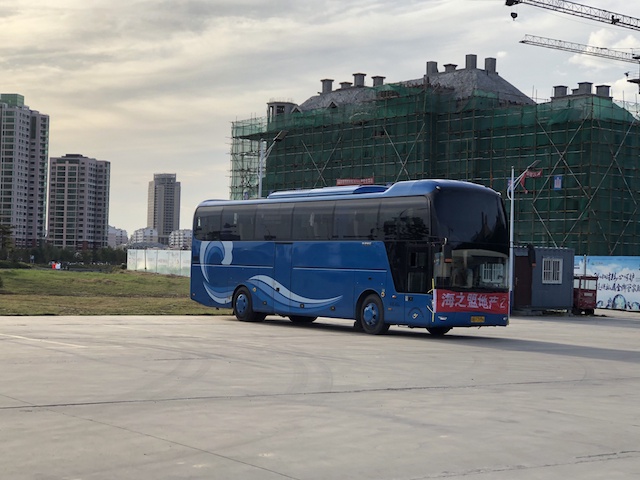 在乳山海景房新楼盘旁停着的“看房团”大巴车