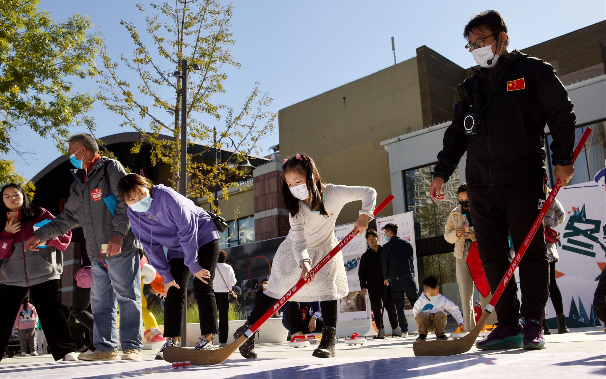 冬奥体验互动区，家长和孩子正在体验冰球射门等迷你冬奥会活动。摄影/新京报记者 李凯祥