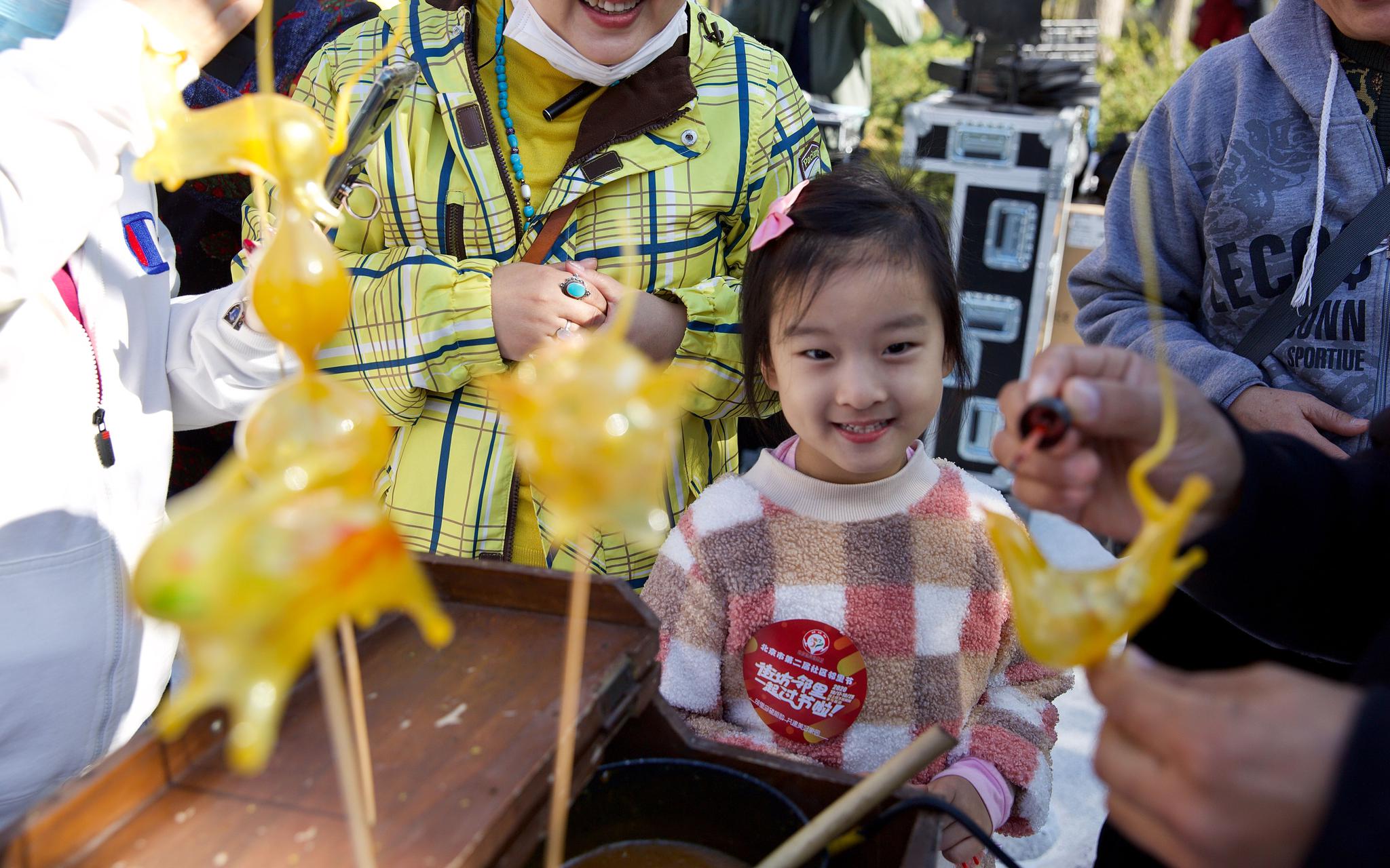 非遗展示互动区，一位小孩正在围观“非遗”项目吹糖人。摄影/新京报记者 李凯祥