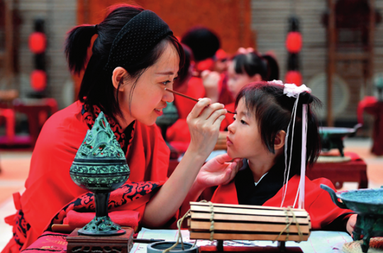 9月13日，西安大唐西市博物馆，家长在孩子额头上点朱砂，进行“朱砂开智”刘潇摄 / 本刊