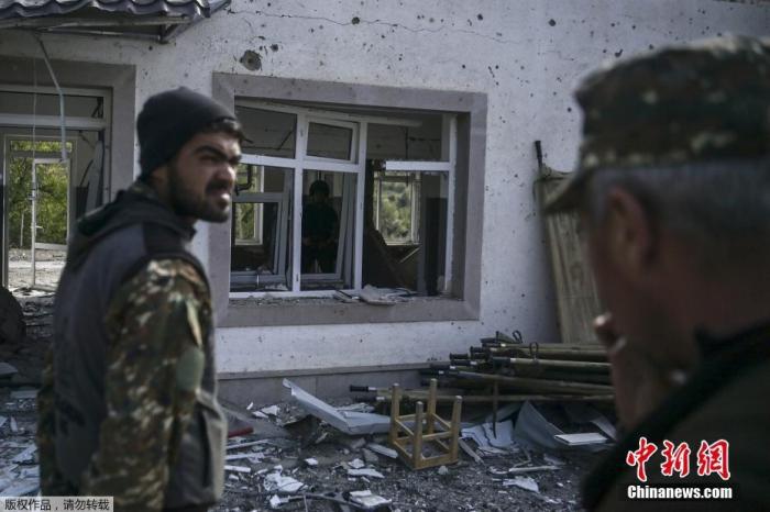 当地时间10月15日，亚美尼亚和阿塞拜疆的冲突在纳卡地区持续进行，Martakert地区一家医院在战火中被摧毁。图为亚美尼亚士兵站在被部分摧毁的军事医院建筑前。