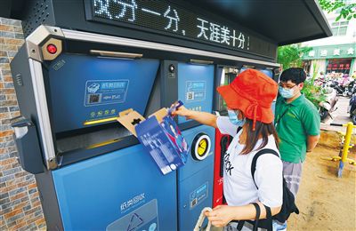 10月19日,在三亚金鸡岭路社区智能垃圾分类投放点,居民正在分类投放