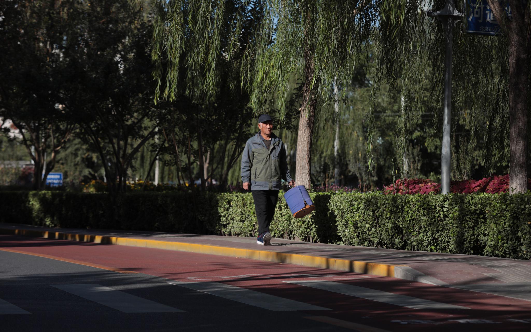 北京市西城区广外街道莲花河西侧路，一位市民正提着鸟笼遛弯。摄影/新京报记者 王嘉宁