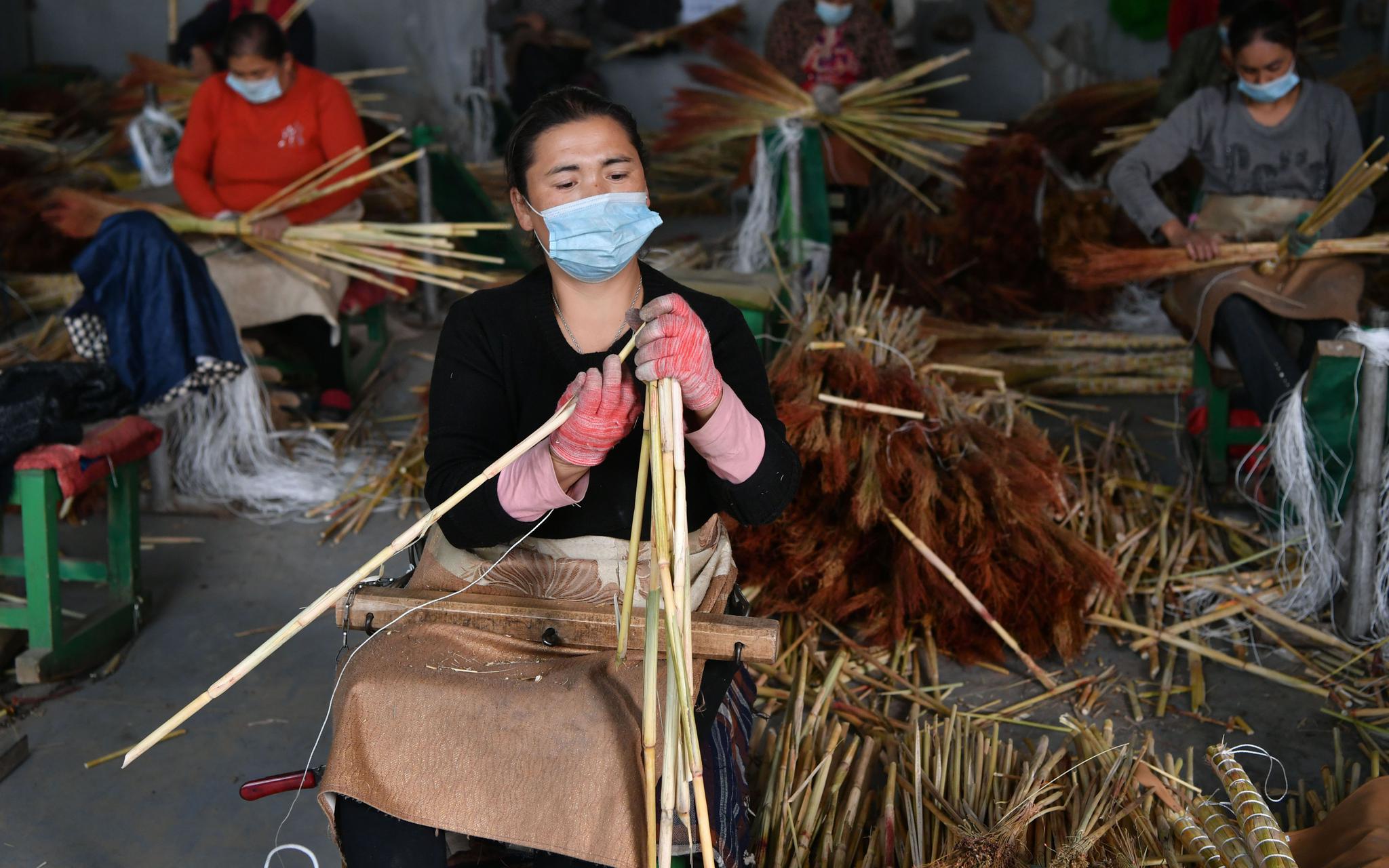 10月14日，在阿克萨拉依乡佳美扫把制作中心，维吾尔族女工正在制作扫把。新京报记者 吴江 摄