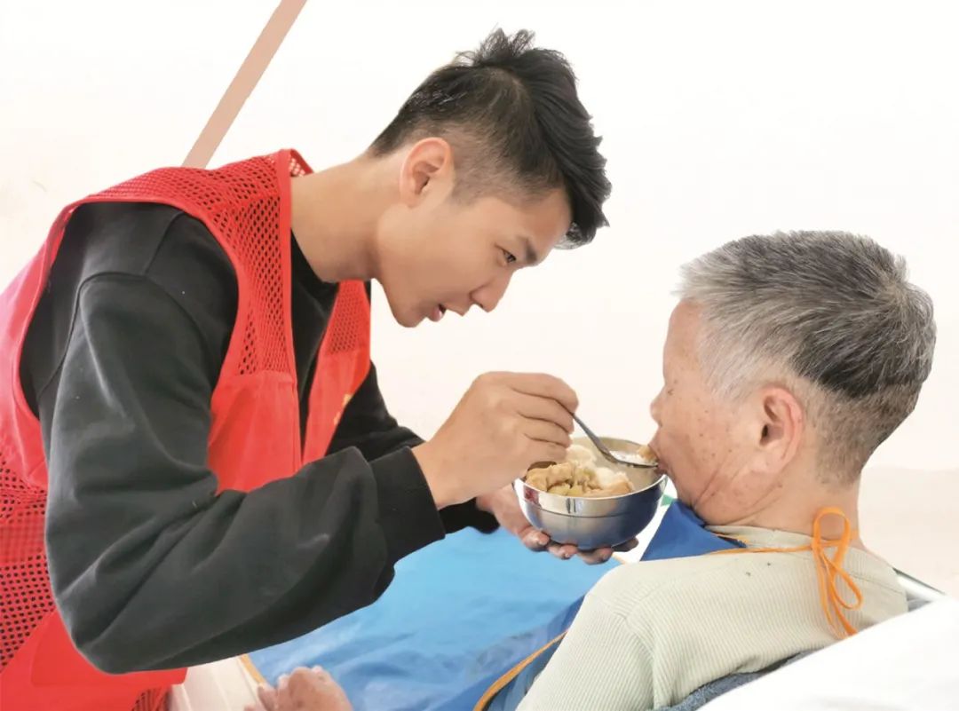 王旭佳在给一位老人喂饭.