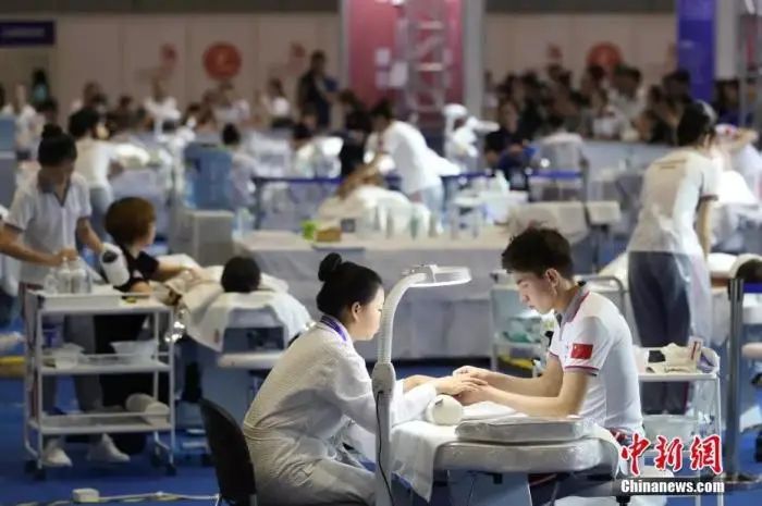 原料图:2018中国技能大赛现场,美容师正在给体验者做指甲。张亨伟 摄