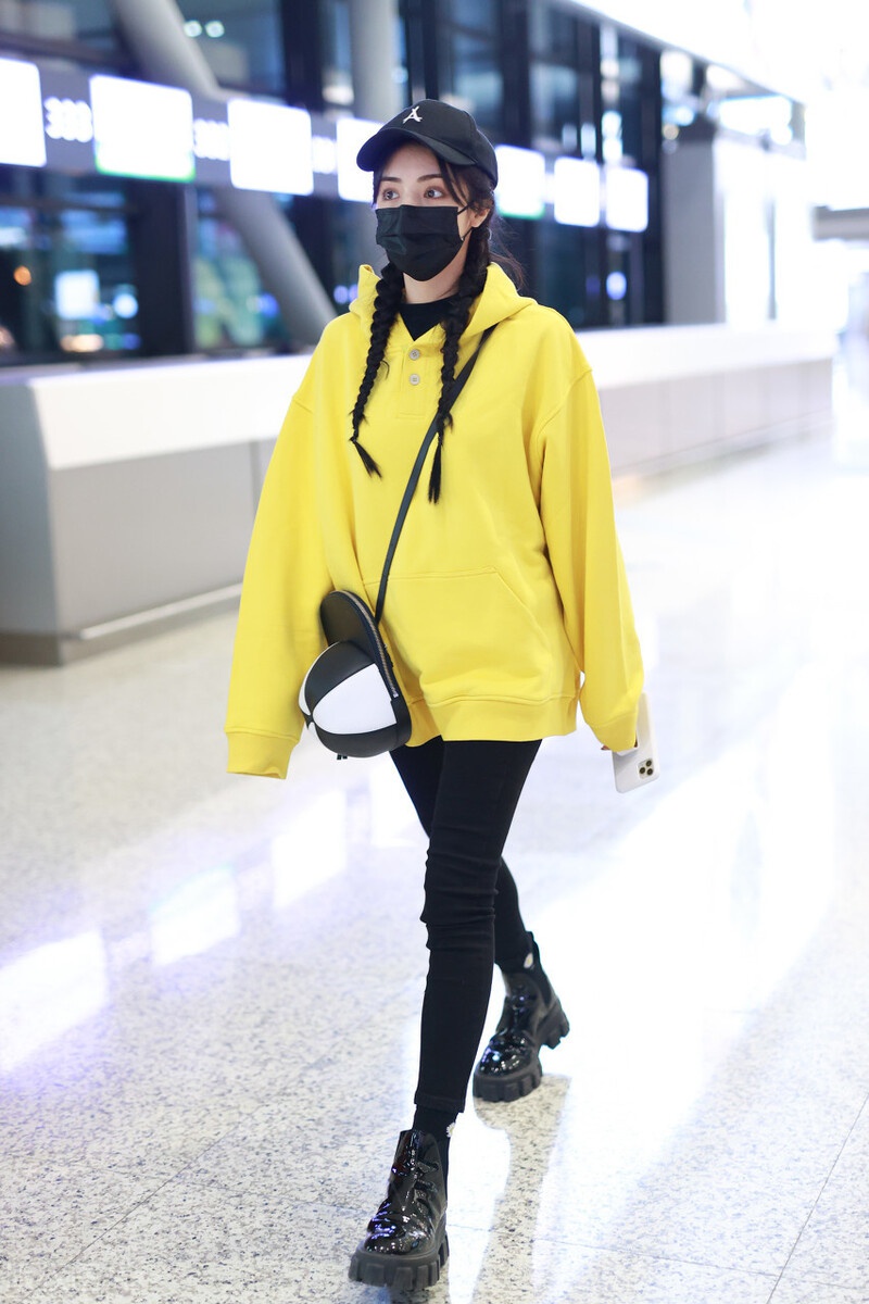 麦迪娜一袭黄色的连帽卫衣现身机场,棒球帽形状的包包超可爱