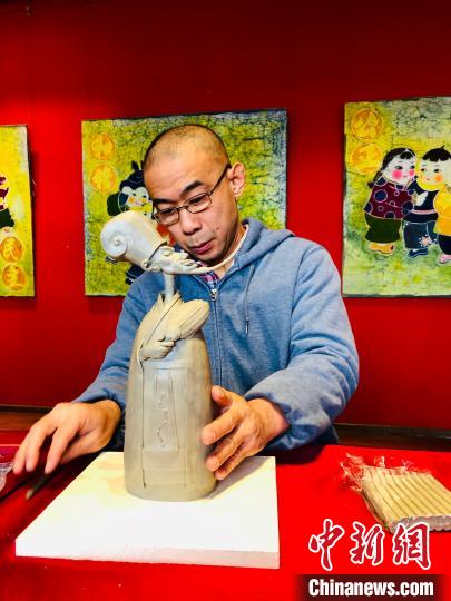 听力障碍的林开开是山东省青年美术家协会会员、山东省城市雕塑协会会员。图为林开开和他的作品《孔明》。　王祖敏 摄