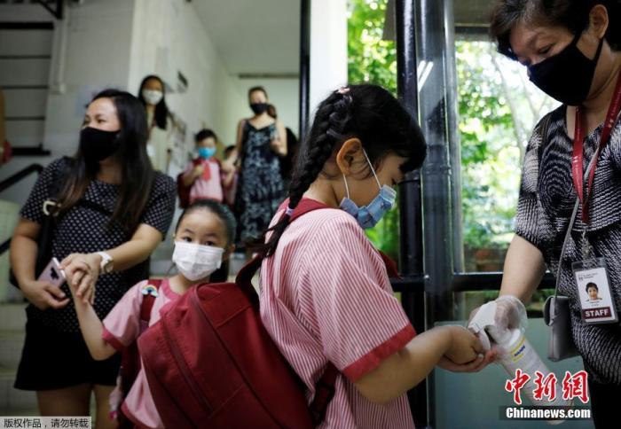 图为当地时间6月2日，新加坡校重新开学，幼儿园学生进教室前用洗手液消毒。