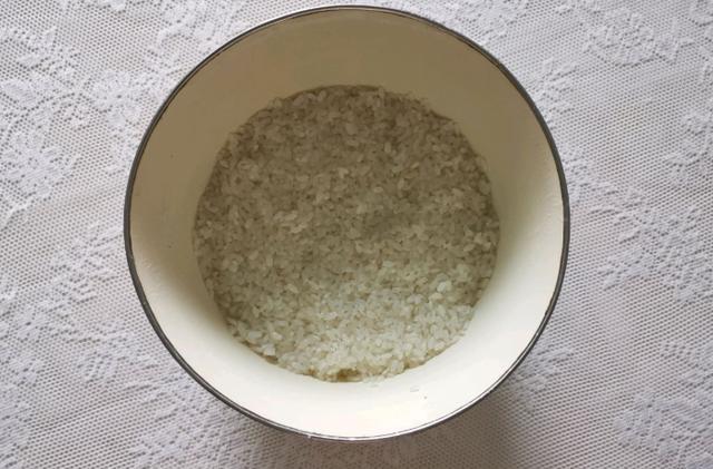 4,倒进150克的凉开水,戴上一次性的手套,把酒曲,水还有米粒轻轻地抓拌