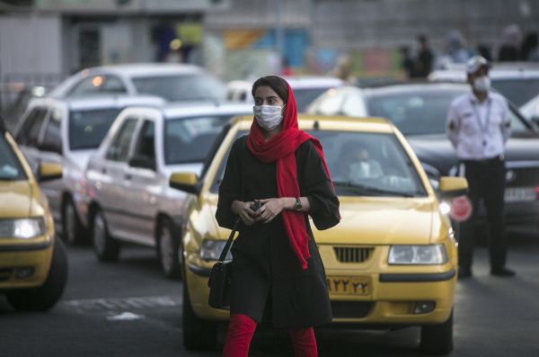  9月26日，一名女子佩戴口罩在伊朗德黑兰过马路。新华社发