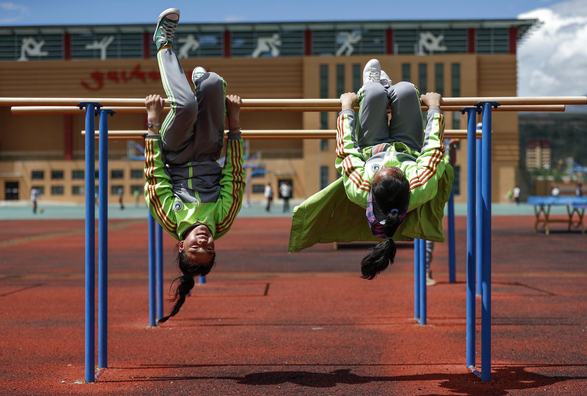 四川省阿坝藏族羌族自治州阿坝县藏文中学校学生在体育课上练习翻双杠