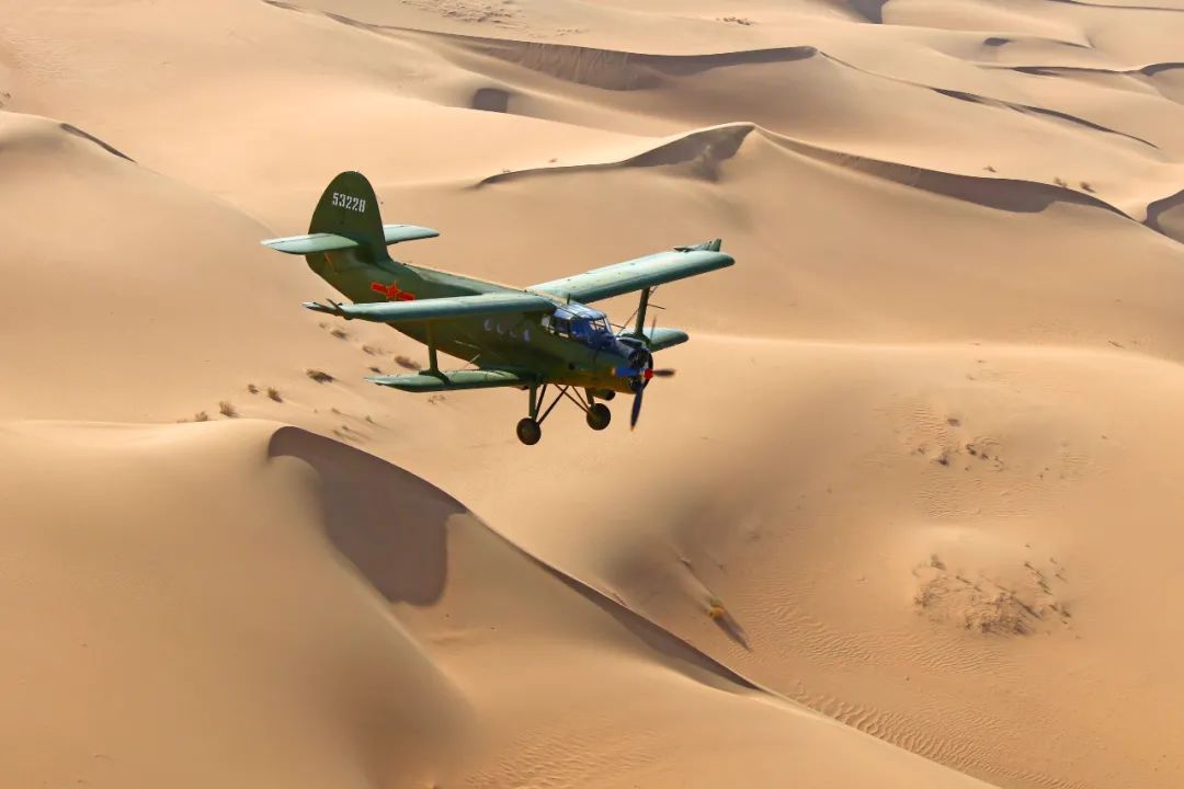 空军运-5飞机在沙漠上空飞播造林作业,支援贫困地区生态文明建设