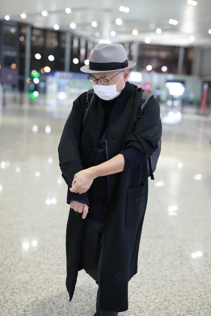 徐峥穿搭了一件藏青色的打底衫,外搭是一件黑色的风衣外套.