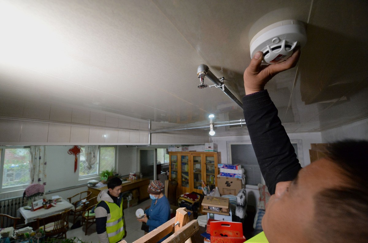 人在尹阿姨家安装烟感报警器,尹阿姨详细询问了使用方法.