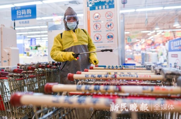 图说：昨晚十点，仙霞路上一家超市结束营业，工作人员对购物车进行消毒 新民晚报记者 陈梦泽 摄