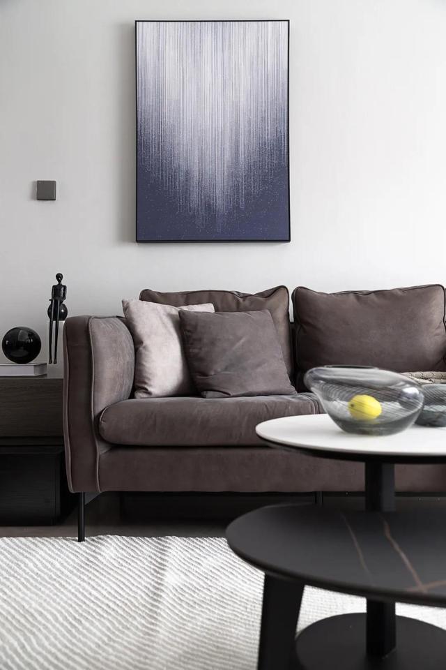 一副渐变色的线条装饰画给墙面增加了色彩;绒皮质感的暖棕色沙发是