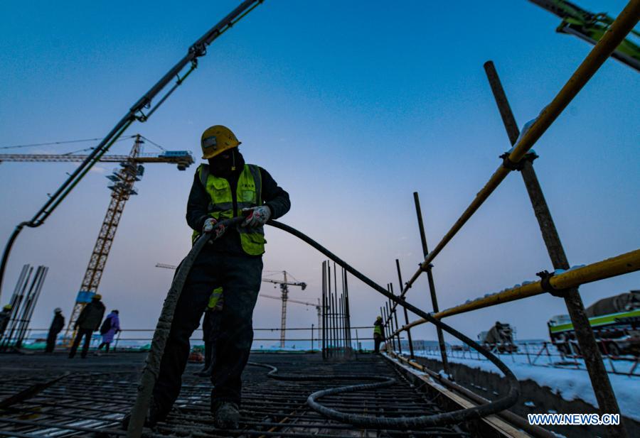A worker of the China Construction Third Bureau Co., Ltd. pours concrete at the site of the Urumqi Airport expansion project in Urumqi, northwest China's Xinjiang Uygur Autonomous Region, Dec. 3, 2020. The main structure of Section I of the south waiting corridor of the Urumqi Airport expansion project was closed Friday amid cold weather. The airport expansion, also the largest individual-building project so far in Xinjiang, is expected to be completed and put to operation by 2023. (Xinhua/Wang Fei)