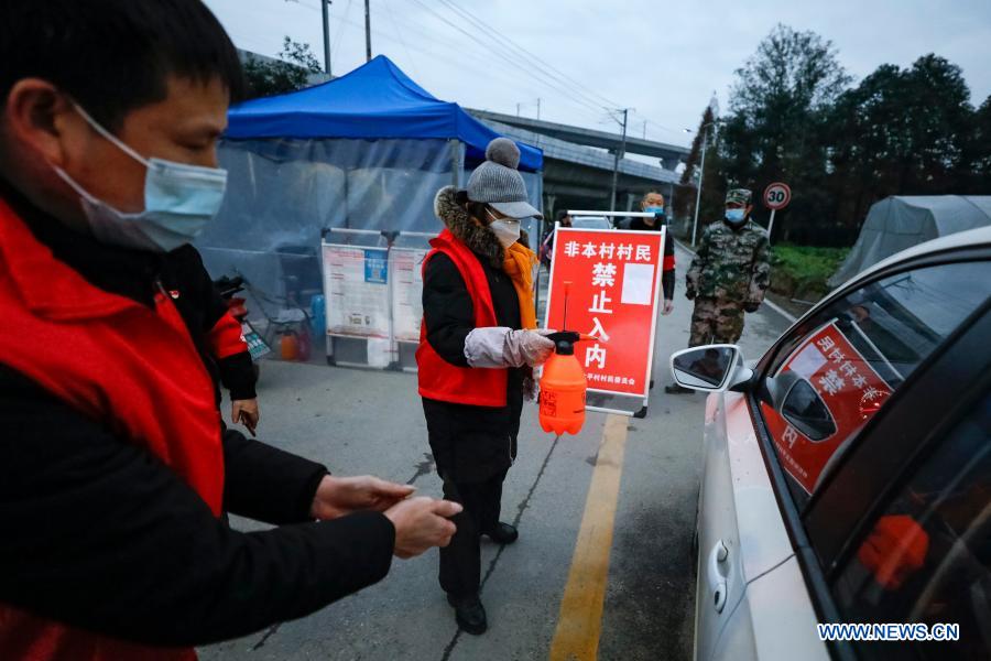 Volunteers sanitize a car at a checkpoint in Taiping Village of Pidu District in Chengdu, southwest China's Sichuan Province, Dec. 9, 2020. (Xinhua/Shen Bohan)