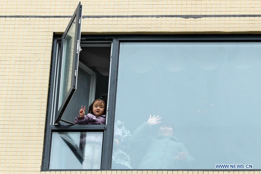 A girl makes a V sign from her home at a quarantined residential community in Chenghua District of Chengdu, southwest China's Sichuan Province, Dec. 10, 2020. The community has been re-classified as a COVID-19 medium-risk area starting from 9:00 p.m. on Dec. 8. Its 300-plus households have all been kept in home quarantine. About 70 community workers and volunteers have been assigned to deliver the residents' daily necessities. (Xinhua/Shen Bohan)