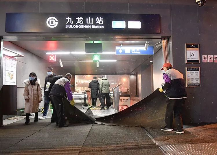 九龙山地铁站出口,工作人员铺上地毯防滑.