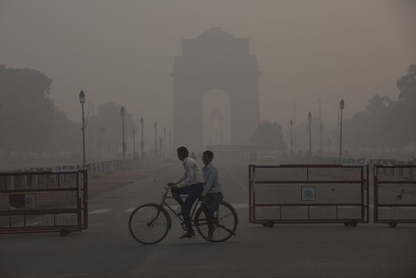 2019年11月13日，在印度新德里，两名男子经过雾霾中的印度门。（新华社）