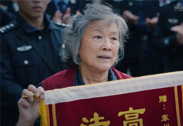 和获奖者合照留念的时候,其貌不扬的胡雪娥老太太手举着锦旗来凑热闹
