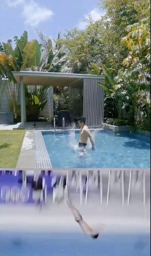 田亮穿着泳裤,站在游泳池旁边,平地后空翻入水,而且水里还放着一个小