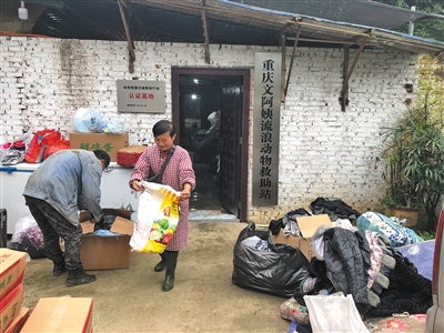 文军红和工人在修整善心人送来的旧衣服。二十年间,文军红救下上千只漂泊猫狗,成为重庆市著名的漂泊动物援助人,创建了当地周围数一数二的幼我漂泊动物援助站。