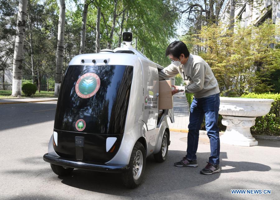 A member of staff takes goods from a 5G unmanned delivery car at the Beijing Institute of Technology in Beijing, capital of China, April 6, 2020. With the development of new technologies such as the 5G, artificial intelligence and BeiDou Navigation Satellite System (BDS), unmanned technology is injecting impetus into traditional industries as well as making people's life easier and more convenient in China, and bringing about profound innovation and transformation. From commerce, agriculture, transportation, industrial production to environmental protection, China has been embracing this emerging technology in various fields in recent years as it strives to promote high-quality development. (Xinhua/Ren Chao)