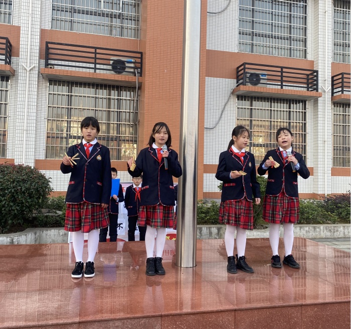 12月21日,四名手拿快板的小学生精神抖擞地走上南县玉潭学校的升旗台